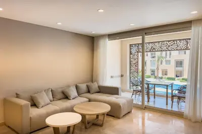 a living room with a couch and tables and a patio at Soothing & Stilly 2BDR Mangroovy Pool & Beach Access in Hurghada