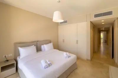 a bedroom with a white bed with towels on it at Soothing & Stilly 2BDR Mangroovy Pool & Beach Access in Hurghada