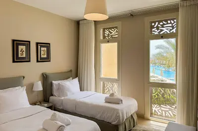 two beds in a hotel room with a window at Summer Breeze 2 BDR Pool Sea View Mangroovy in Hurghada