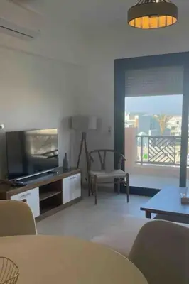 a living room with a television and a table and chairs at 3 Bedrooms with roof in Makadi in Hurghada