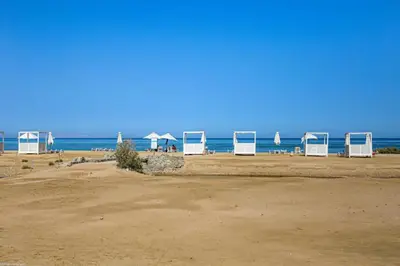 a beach with chairs and umbrellas and the ocean at M Residence with Pool View & Beach Access - El Gouna, Hurghada in Hurghada