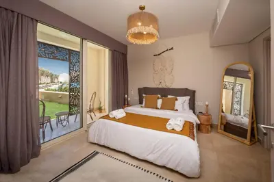a bedroom with a large bed and a large window at Secluded & Bespoke 1 BDR Apt with Pool View & Beach access in Hurghada