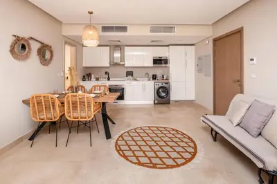 a kitchen and living room with a table and chairs at Secluded & Bespoke 1 BDR Apt with Pool View & Beach access in Hurghada