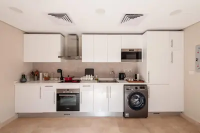 a kitchen with white cabinets and a dishwasher at Secluded & Bespoke 1 BDR Apt with Pool View & Beach access in Hurghada