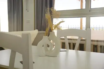 a table with two white chairs and a vase with flowers at Kite and Dive Home in Hurghada
