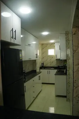 a kitchen with white cabinets and a black refrigerator at Kite and Dive Home in Hurghada