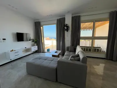 a living room with a couch and a flat screen tv at Kite and Dive Home in Hurghada