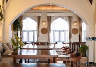 a restaurant with tables and chairs and windows at Aro Kato Nubian Guest House in Aswan