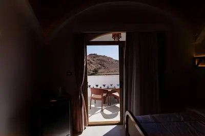 a room with a door open to a balcony with a table at Aro Kato Nubian Guest House in Aswan
