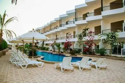 a hotel with a swimming pool with chairs and umbrellas at Capitan house beside Bellagio hotel 5 minutes from El gouna in Hurghada