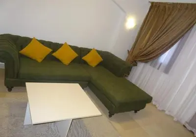 a green couch with yellow pillows in a living room at Warm One Bedroom at West Golf Y62 in Hurghada