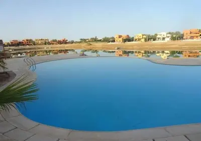 a blue swimming pool with buildings in the background at Warm One Bedroom at West Golf Y62 in Hurghada