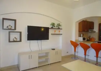 a living room with a tv and two orange chairs at Warm One Bedroom at West Golf Y62 in Hurghada