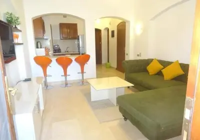 a living room with a green couch and orange chairs at Warm One Bedroom at West Golf Y62 in Hurghada