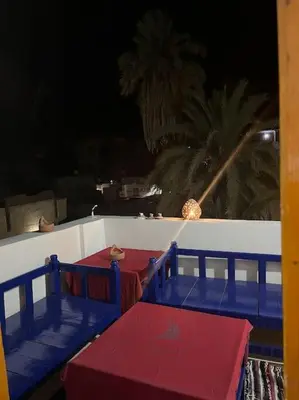 a room with blue and red tables and palm trees at Shamandy house same same but different in Jazīrat Aswān