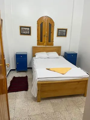 a bedroom with a bed with a wooden headboard at Shamandy house same same but different in Jazīrat Aswān
