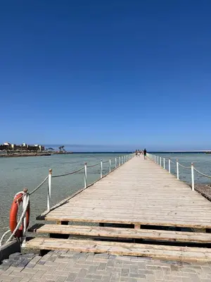 a wooden pier with a boat on the water at Scandic Resort Hurghada Red Sea in Hurghada