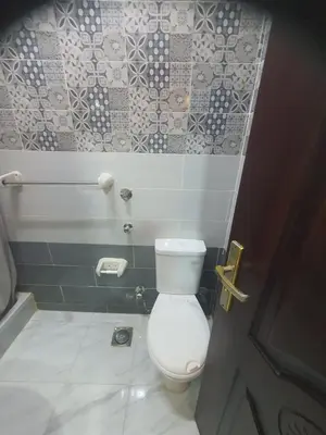 a bathroom with a toilet and a tile wall at Abeer Suites 4 basement in Hurghada