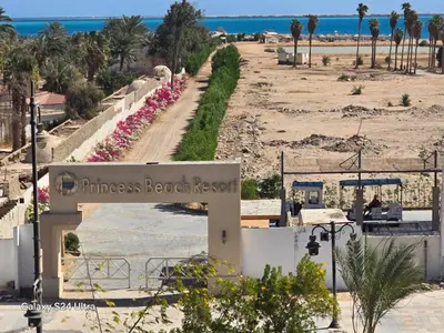 a sign for the entrance to a beach with pink flowers at Sea view Princessa Resort in Hurghada