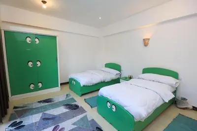 two beds in a room with green cabinets at Moka Gust House in Luxor