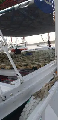 a bed on a boat with a boat in the background at Mama Africa Felucca in Aswan