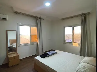 a bedroom with a large bed and two windows at Beach Side 1 Bedroom Apartment in Hurghada