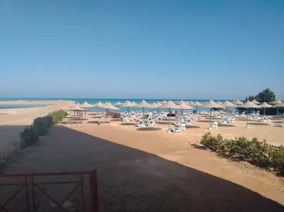 a beach with a bunch of chairs and umbrellas at Beach Side 1 Bedroom Apartment in Hurghada