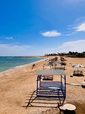 a beach with chairs and umbrellas and the ocean at Astonishing Twin Villa in O-C in Coraya Bay