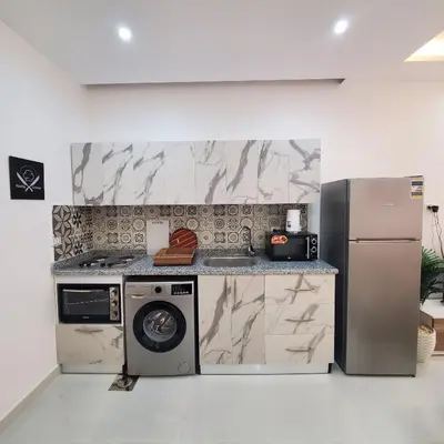 a kitchen with a refrigerator and a washer and dryer at Hurghada Airport Aparthotel - SAHLHOMES in Hurghada