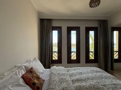a bedroom with a white bed with three windows at The Charming Beachfront Retreat in Fanadir in Hurghada