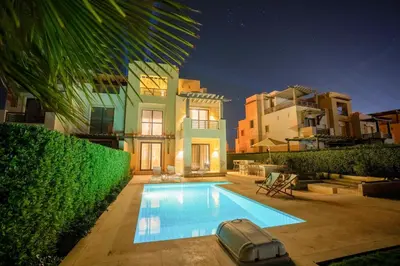 a swimming pool in front of a house at night at Luxury 4BR + Nanny Villa • Ancient Sands in Hurghada