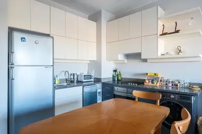a kitchen with a wooden table and a refrigerator at Chic Cyan 3BR Apt. • Prime Location in Hurghada