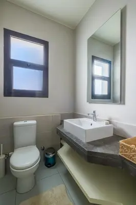 a bathroom with a toilet and a sink and a mirror at Chic Cyan 3BR Apt. • Prime Location in Hurghada