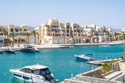 a group of boats docked in a harbor with buildings at Freshly Minted: 1BR Fanadir Marina in Hurghada