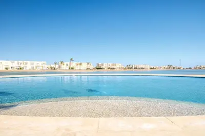 a swimming pool with blue water and buildings in the background at Shedwan 2 Bdr Ground Floor in Hurghada