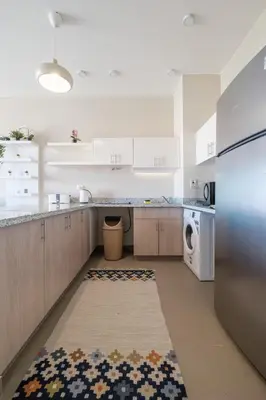 a large kitchen with white cabinets and a dishwasher at Chic Tawila 1BR • Pristine & Modern in Hurghada