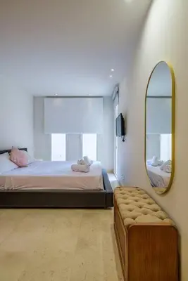 a room with two beds and a mirror and a bench at Stylish 1BR • Scarab Main Pool Access in Hurghada