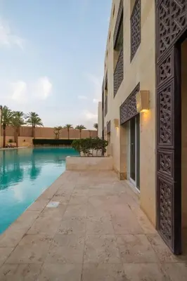 a building with a swimming pool next to a building at Stylish 1BR • Scarab Main Pool Access in Hurghada