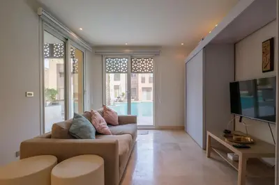 a living room with a couch and a tv at Stylish 1BR • Scarab Main Pool Access in Hurghada
