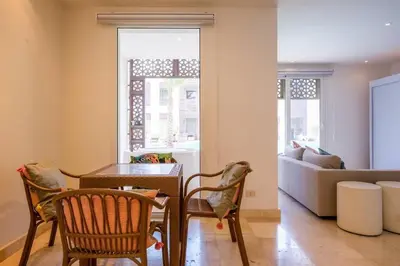 a living room with a table and chairs and a couch at Stylish 1BR • Scarab Main Pool Access in Hurghada