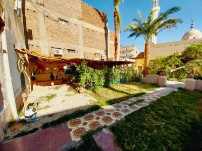a yard with a building and palm trees and a sidewalk at Osiris Hotel Luxor \u60a8\u5728\u76e7\u514b\u7d22\u7684\u7b2c\u4e8c\u500b\u5bb6 in Luxor