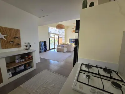 a kitchen with a stove and a living room at Somabay Beach House BW in Hurghada