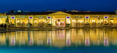 a building with lights on the water at night at HRG Hurghada Hotel Apartments Aqua park - By MAMO Property in Hurghada
