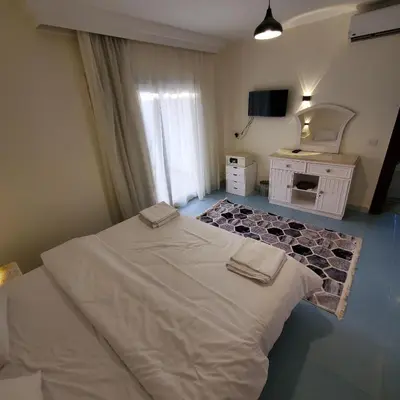 a bedroom with a large white bed and a mirror at HRG Hurghada Hotel Apartments Aqua park - By MAMO Property in Hurghada