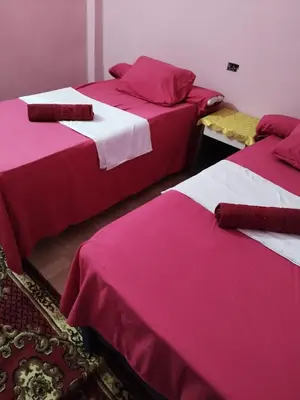three beds in a room with pink and white sheets at Grand Square Hostel Luxor in Luxor