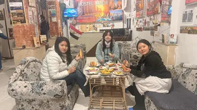 three women sitting at a table eating food at Grand Square Hostel Luxor in Luxor