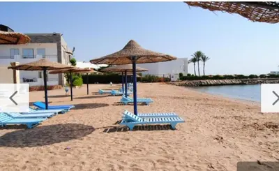 a group of blue chairs and umbrellas on a beach at Cecelia Beach Resort - 2 Rooms with terace in Hurghada