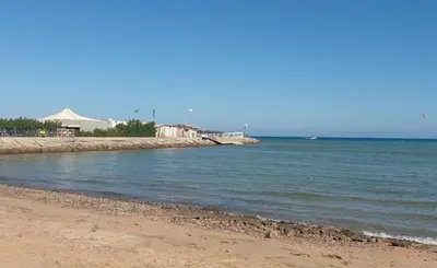 a beach with the ocean and a pier in the background at Cecelia Beach Resort - 2 Rooms with terace in Hurghada