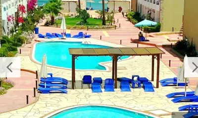a pool with blue chairs and umbrellas at Cecelia Beach Resort - 2 Rooms with terace in Hurghada