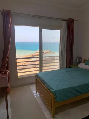 a bedroom with a bed and a view of the ocean at Quiet quarter and private beach in Hurghada